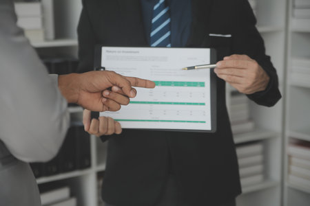 Financial analysts analyze business financial reports on a digital tablet planning investment...