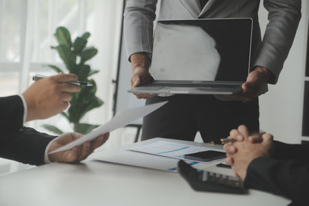 Financial analysts analyze business financial reports on a digital tablet planning investment project during a discussion at a meeting of corporate showing the results of their successful teamwork.の写真素材