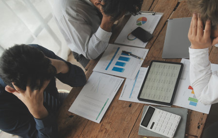 Financial analysts analyze business financial reports on a digital tablet planning investment project during a discussion at a meeting of corporate showing the results of their successful teamwork.の写真素材