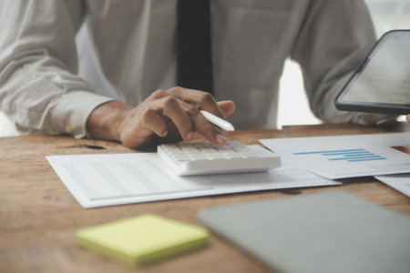 Financial analysts analyze business financial reports on a digital tablet planning investment project during a discussion at a meeting of corporate showing the results of their successful teamwork.の写真素材