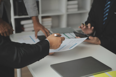 Financial analysts analyze business financial reports on a digital tablet planning investment project during a discussion at a meeting of corporate showing the results of their successful teamwork.の写真素材