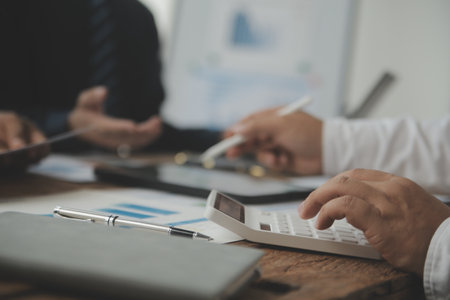 Financial analysts analyze business financial reports on a digital tablet planning investment project during a discussion at a meeting of corporate showing the results of their successful teamwork.の写真素材