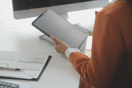 Asian Businesswoman Using laptop computer and working at office with calculator document on desk, doing planning analyzing the financial report, business plan investment, finance analysis concept.の写真素材