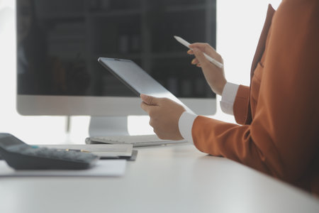 Asian Businesswoman Using laptop computer and working at office with calculator document on desk, doing planning analyzing the financial report, business plan investment, finance analysis concept.の写真素材