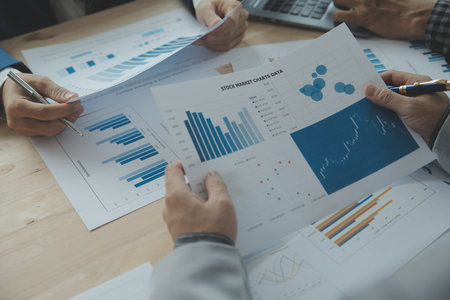 Group of confident business people point to graphs and charts to analyze market data, balance sheet,...