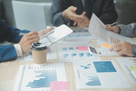Group of confident business people point to graphs and charts to analyze market data, balance sheet, account, net profit to plan new sales strategies to increase production capacity.の写真素材