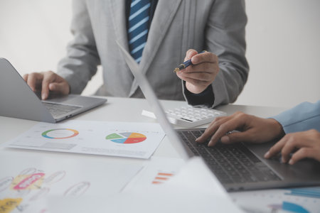 Financial analysts analyze business financial reports on a digital tablet planning investment project during a discussion at a meeting of corporate showing the results of their successful teamwork.の写真素材