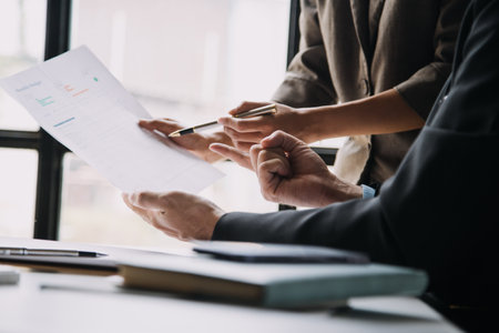 Financial analysts analyze business financial reports on a digital tablet planning investment project during a discussion at a meeting of corporate showing the results of their successful teamwork.の写真素材