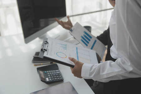 Group of confident business people point to graphs and charts to analyze market data, balance sheet, account, net profit to plan new sales strategies to increase production capacity.の写真素材