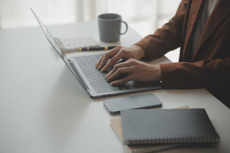 Attractive smiling young asian business woman work at home office, Asian woman working on laptop computer holding tablet.の写真素材