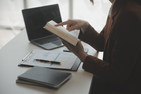 Attractive smiling young asian business woman work at home office, Asian woman working on laptop computer holding tablet.の写真素材