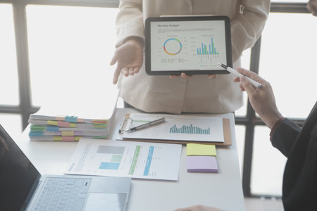 Financial analysts analyze business financial reports on a digital tablet planning investment project during a discussion at a meeting of corporate showing the results of their successful teamwork.の写真素材