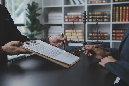 Business and lawyers discussing contract papers with brass scale on desk in office. Law, legal services, advice, justice and law concept picture with film grain effectの写真素材