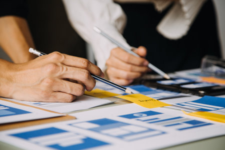 Close up ux developer and ui designer brainstorming about mobile app interface wireframe design on table with customer breif and color code at modern office.Creative digital development agencyの写真素材