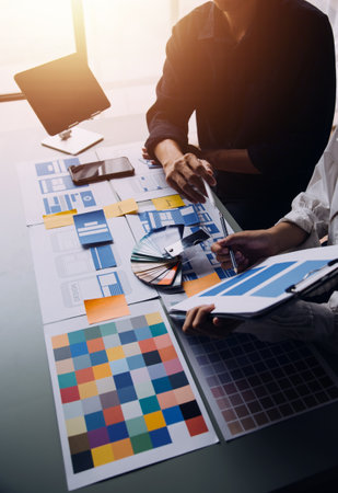 Close up ux developer and ui designer brainstorming about mobile app interface wireframe design on table with customer breif and color code at modern office.Creative digital development agencyの写真素材