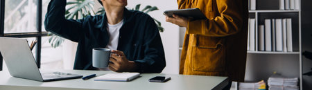 Entrepreneur Asian businessman and businesswoman discussing new business project in tablet in modern Meeting In Modern Office, Asian business casual concept.の写真素材