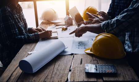 Two Specialists Inspect Commercial, Industrial Building Construction Site. Real Estate Project with Civil Engineer, Investor Use Laptop. In the Background Crane, Skyscraper Concrete Formwork Framesの写真素材