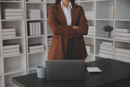 Attractive smiling young asian business woman work at home office, Asian woman working on laptop computer holding tablet.の写真素材