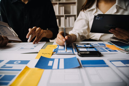 Close up ux developer and ui designer brainstorming about mobile app interface wireframe design on table with customer breif and color code at modern office.Creative digital development agencyの写真素材