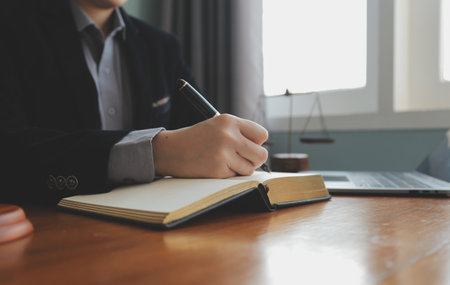 Business and lawyers discussing contract papers with brass scale on desk in office. Law, legal services, advice, justice and law concept picture with film grain effectの写真素材