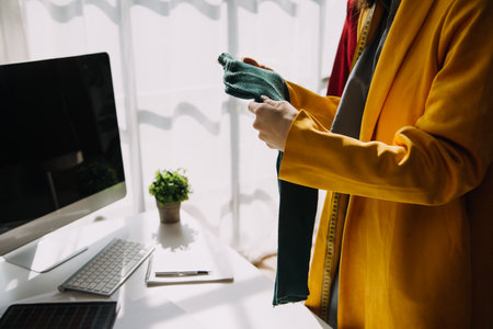 Fashion designer l young asian woman working using laptop, tablet and smiling while standing in workshop Responding on businessの写真素材