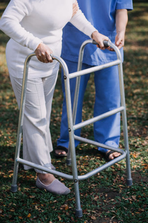young asian physical therapist working with senior woman on walking with a walkerの写真素材