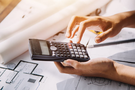 Two Specialists Inspect Commercial, Industrial Building Construction Site. Real Estate Project with Civil Engineer, Investor Use Laptop. In the Background Crane, Skyscraper Concrete Formwork Framesの写真素材