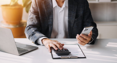 Woman accountant use calculator and computer with holding pen onの写真素材