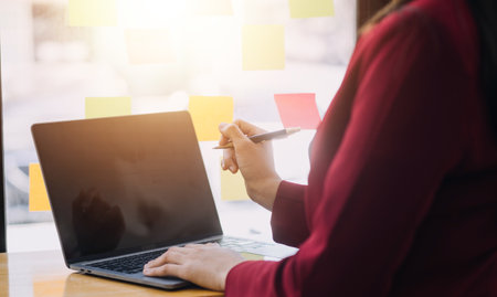 Asian Business woman using calculator and laptop for doing math finance on an office desk, tax, report, accounting, statistics, and analytical research conceptの写真素材
