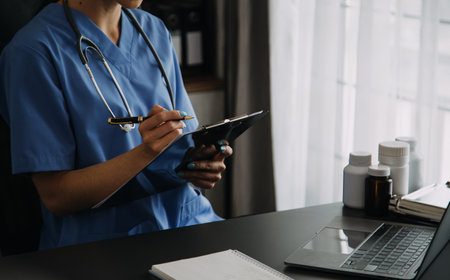 Young doctor with diary sitting at desk in medical clinicの写真素材