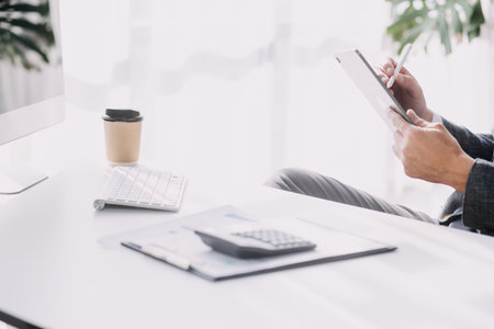 Financial analysts analyze business financial reports on a digital tablet planning investment project during a discussion at a meeting of corporate showing the results of their successful teamwork.の写真素材