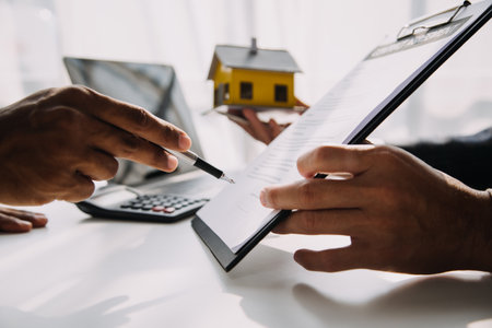 Real estate broker agent presenting and consult to customer to decision making sign insurance form agreement, buy and sell home model, concerning mortgage loan offer for and house insuranceの写真素材