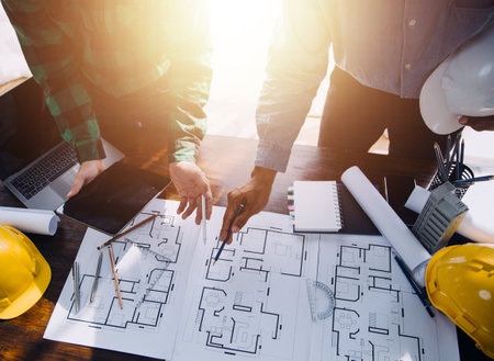 Construction and structure concept of engineer working drawing on blueprint meeting for project working with partner on model building and engineering tools in working site, construction concept.の写真素材