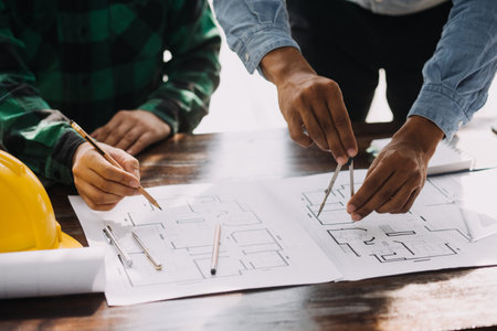 Construction and structure concept of engineer working drawing on blueprint meeting for project working with partner on model building and engineering tools in working site, construction concept.の写真素材
