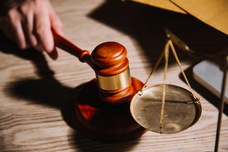 Justice and law concept.Male judge in a courtroom with the gavel, working with, computer and docking keyboard, eyeglasses, on table in morning lightの写真素材