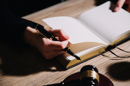 Justice and law concept.Male judge in a courtroom with the gavel, working with, computer and docking keyboard, eyeglasses, on table in morning lightの写真素材