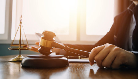 Justice and law concept.Male judge in a courtroom with the gavel, working with, computer and docking keyboard, eyeglasses, on table in morning lightの写真素材
