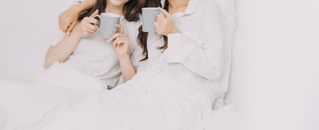 happy teenage girls friend using mobile phone for online shopping in bedroomの写真素材