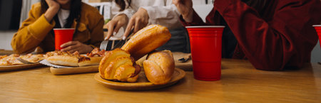 Laughing group of diverse young woman hanging out at home together and eating pizzaの写真素材