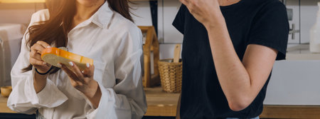 Happy couple using laptop computer preparing healthy food diet vegetable salad at home together. Woman and man are searching recipes, ordering shopping online, watching cooking class in kitchen.の写真素材