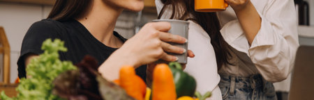 Happy couple using laptop computer preparing healthy food diet vegetable salad at home together. Woman and man are searching recipes, ordering shopping online, watching cooking class in kitchen.の写真素材