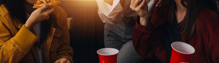 Laughing group of diverse young woman hanging out at home together and eating pizzaの写真素材