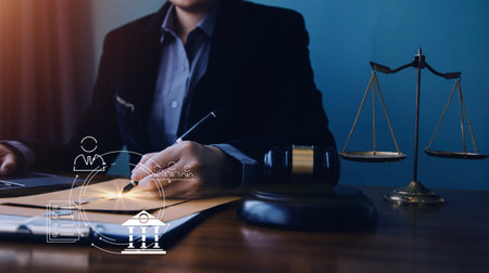 Justice and law concept.Male judge in a courtroom with the gavel, working with, computer and docking keyboard, eyeglasses, on table in morning lightの写真素材