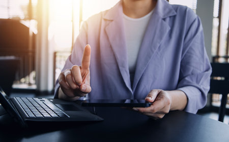Asian Business woman using calculator and laptop for doing math finance on an office desk, tax, report, accounting, statistics, and analytical research conceptの写真素材