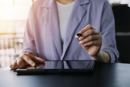 Asian Business woman using calculator and laptop for doing math finance on an office desk, tax, report, accounting, statistics, and analytical research conceptの写真素材