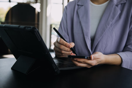 Asian Business woman using calculator and laptop for doing math finance on an office desk, tax, report, accounting, statistics, and analytical research conceptの写真素材