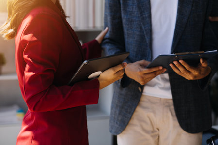 Entrepreneur Asian businessman and businesswoman discussing new business project in tablet in modern Meeting In Modern Office, Asian business casual concept.の写真素材