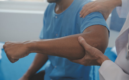 Doctor or Physiotherapist working examining treating injured arm of athlete male patient, stretching and exercise, Doing the Rehabilitation therapy pain in clinic.の写真素材