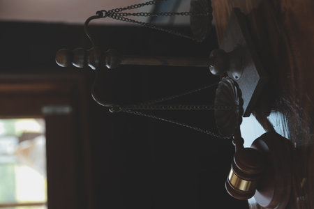 Justice and law concept.Male judge in a courtroom with the gavel, working with, computer and docking keyboard, eyeglasses, on table in morning lightの写真素材