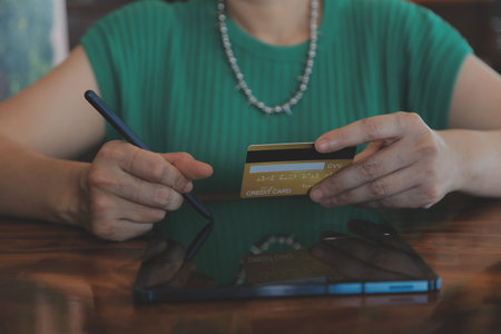 Woman is holding credit card and using laptop computer. Online shopping concept. Close up.
